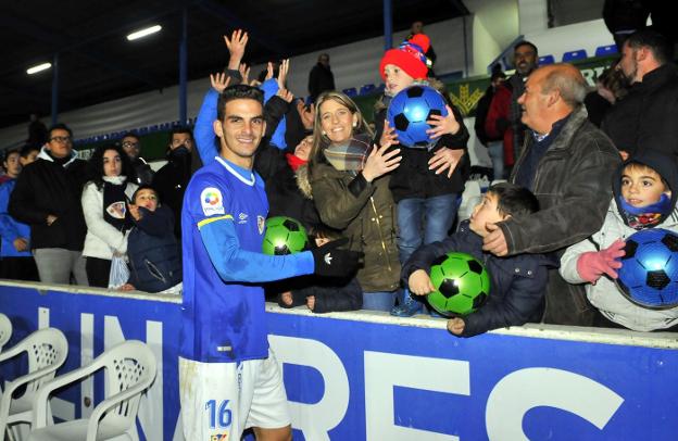 El delantero Pablo Aguilera regalando juguetes a los niños en la grada tras el partido ante el San Pedro./ENRIQUE
