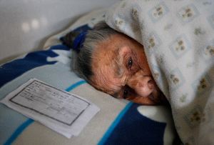 ABUELA. La anciana, postrada en la cama de su chabola junto a una copia del DNI con su edad. / IDEAL/