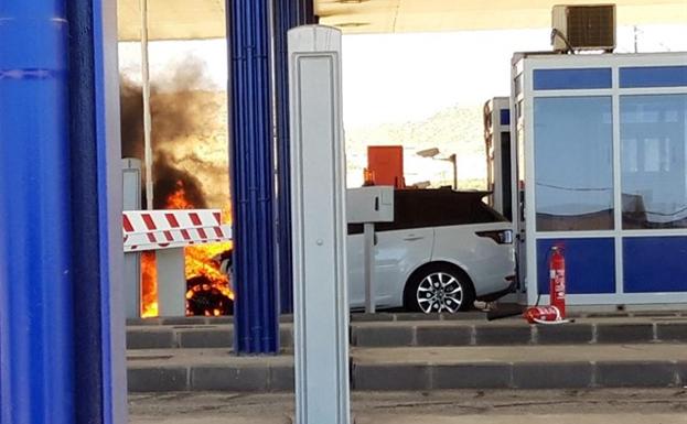 Bomberos trabajan en la extinción de un vehículo incendiado en el peaje de la A-7, a su paso por Vera