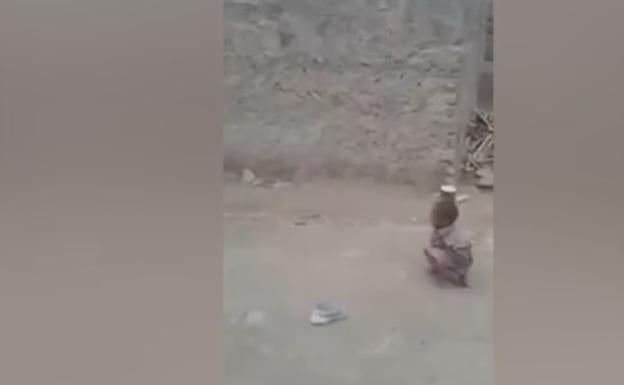 Un niño dispara con un rifle contra una lata sobre la cabeza de su amigo