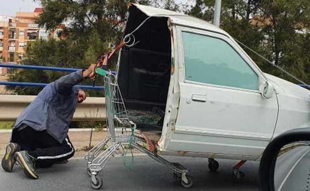 Un hombre circula por la carretera con medio coche sobre un carrito de la compra en Andalucía